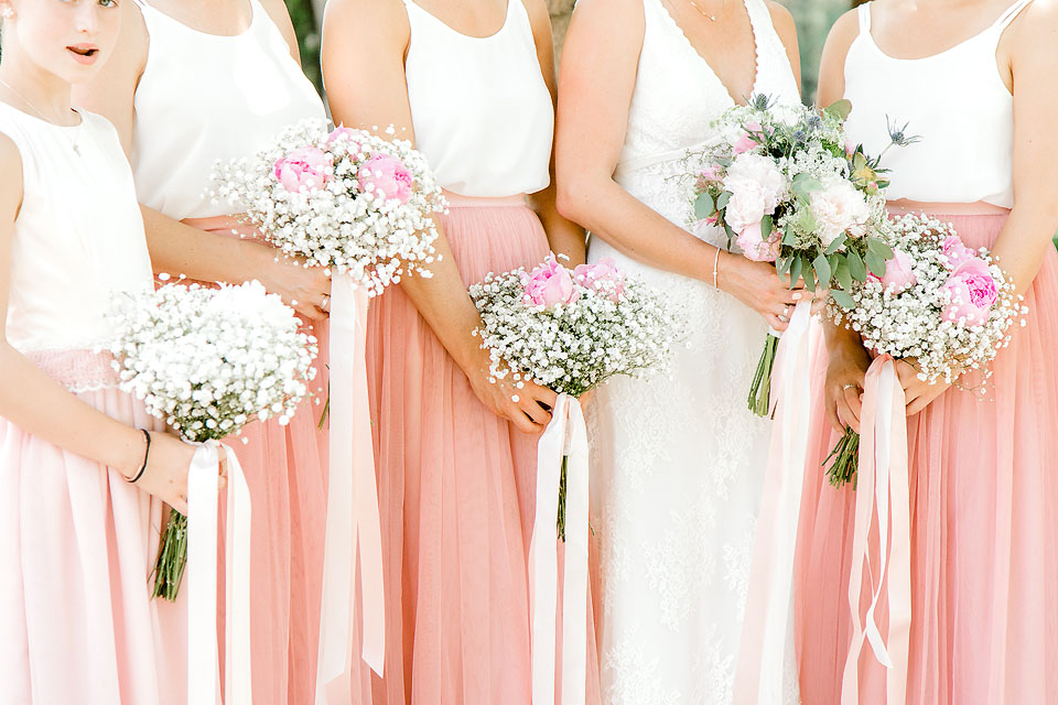 Detail photo of Bridesmaids holding white baby's breath bouquets on a wedding day shot in harsh light. 
