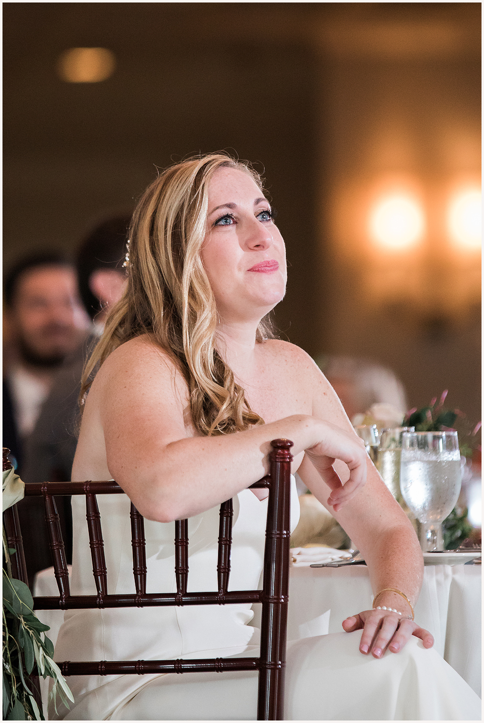 Bride with tears in her eyes, listens to her father give an emotional speech. 
