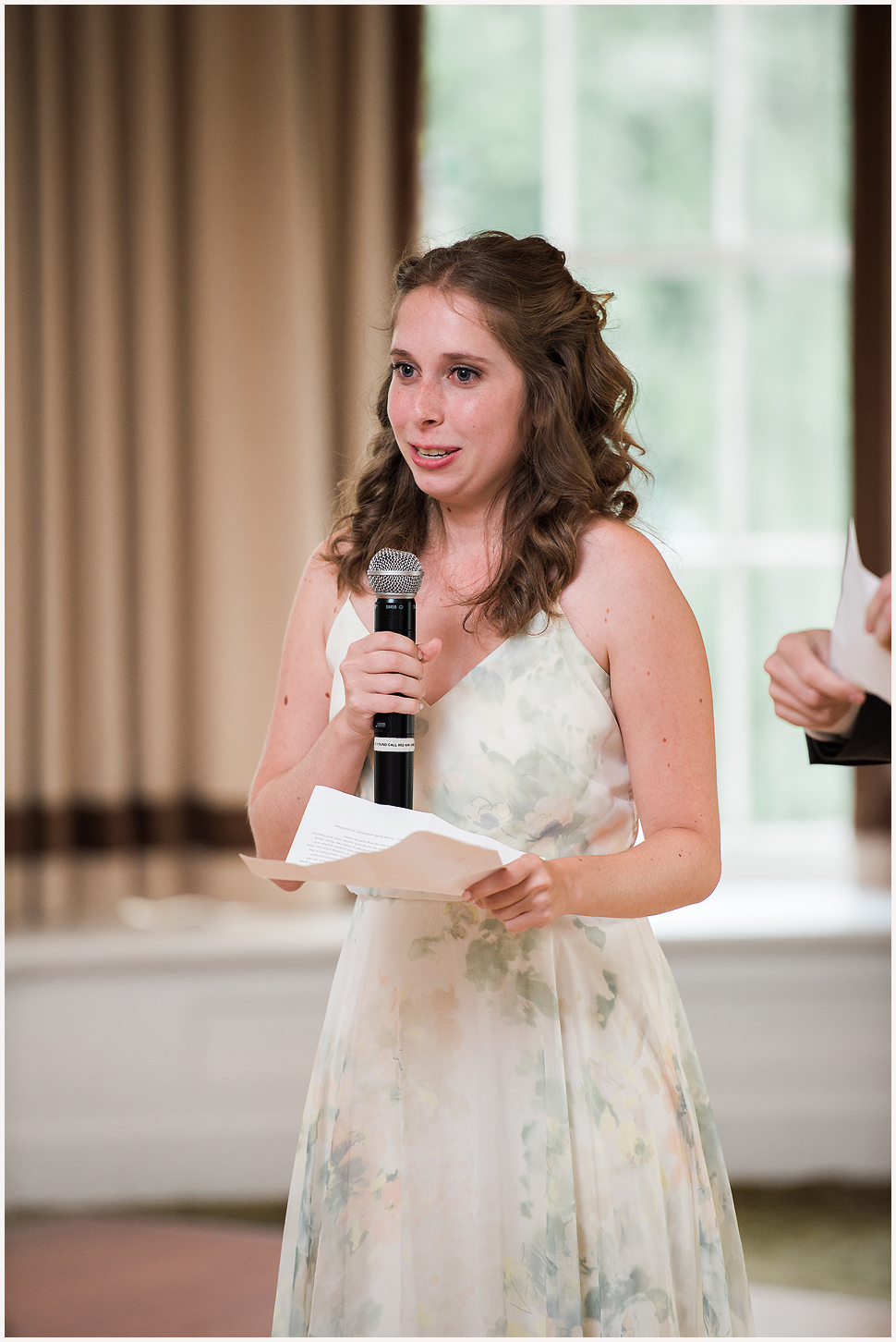 Maid of honor, wearing a soft floral gown, gives a speech at the Equinox Wedding Reception