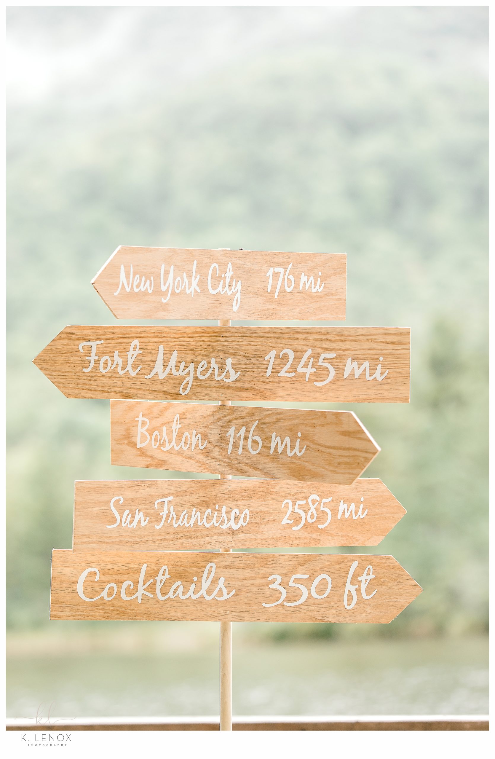 Custom Wooden sign at a wedding reception that shows distances to towns their guests traveled from. 