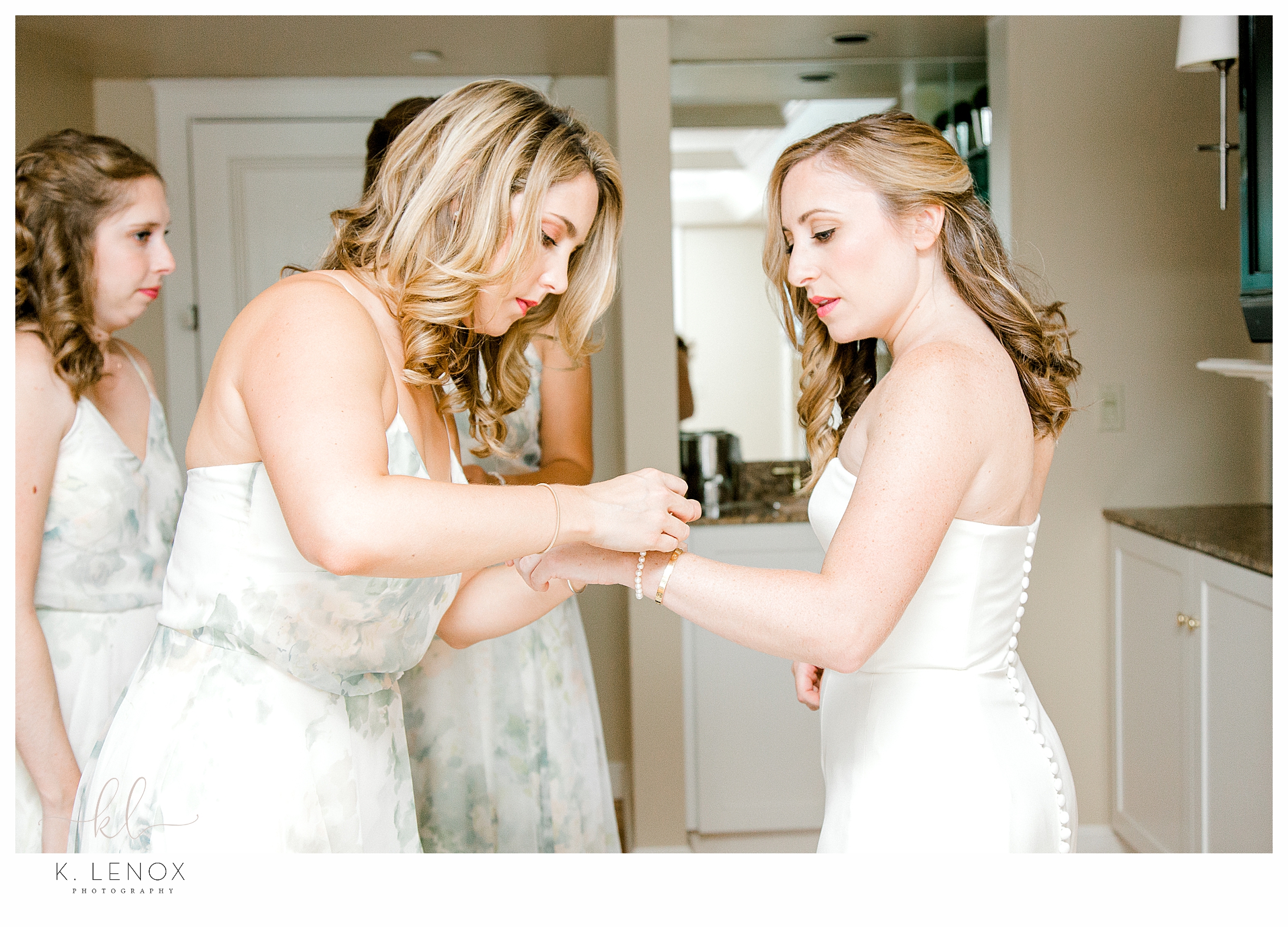 Bridesmaids helping the bride put on her pearl bracelet