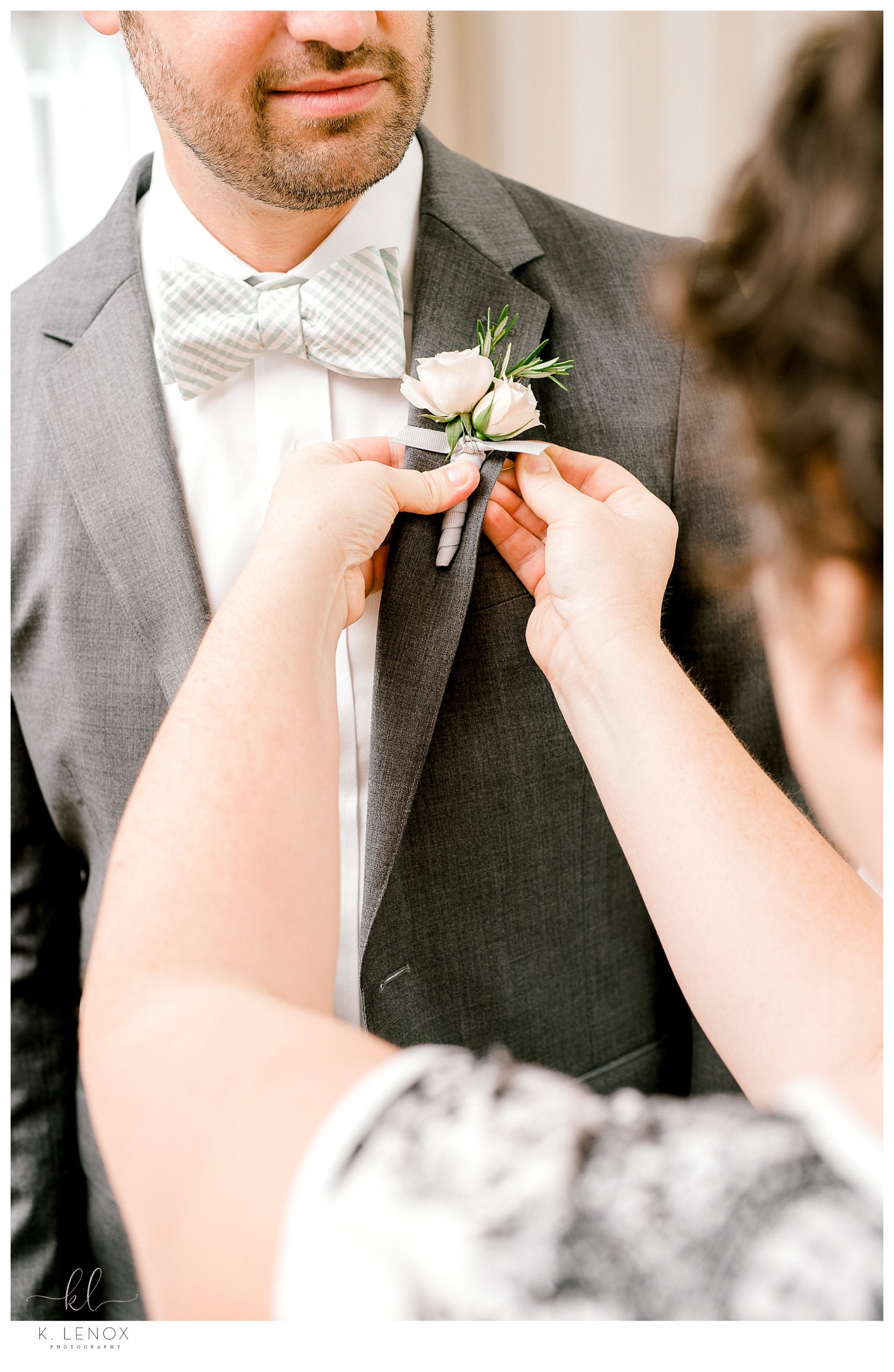 Groom gets his boutonnière put on. 