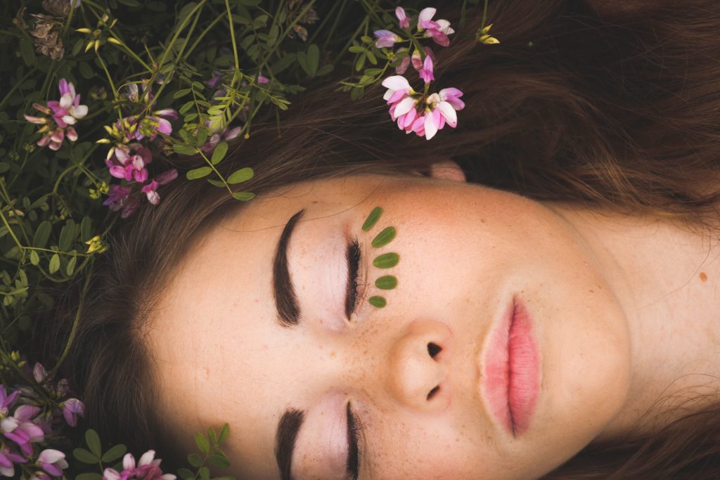 Best Beauty Tips and Trick For Your Wedding Day- Close up of a womans face surrounded by leaves and flowers. 