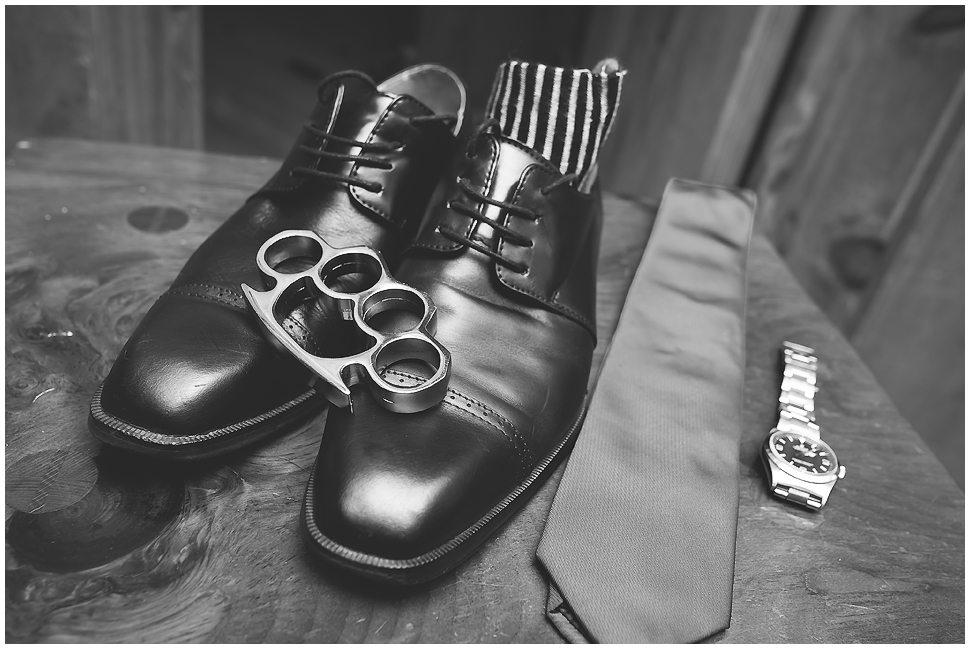 Black and white photo of the grooms details. (Shoes, brass nuckles, tie and watch) 
