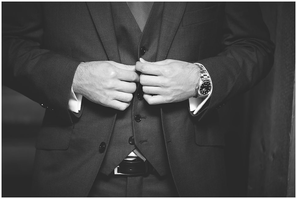 Close up of man buttoning his vest. Black and white photo. 