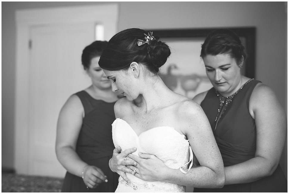 Black and white photo of a beautiful dark haired bride getting her wedding dress on. 