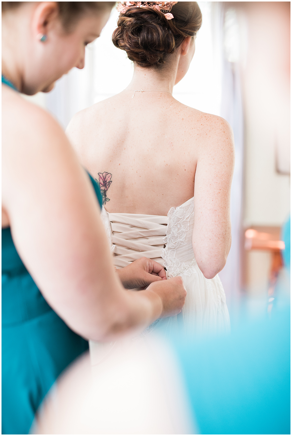 Photo of back of bride's dress as she is getting it tied on her wedding day. 