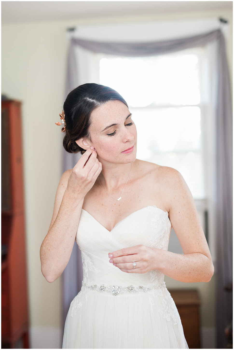 Bride putting on her earrings at Alyson's Orchard farm house. 