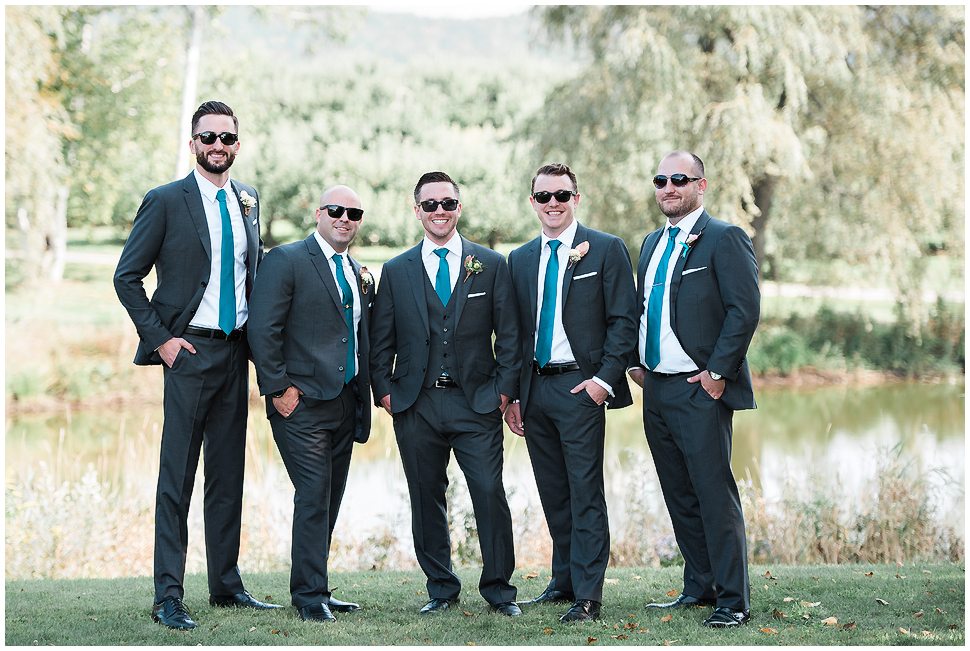 Groomsmen portrait of 5 guys wearing grey suits, teal ties and sunglasses. 