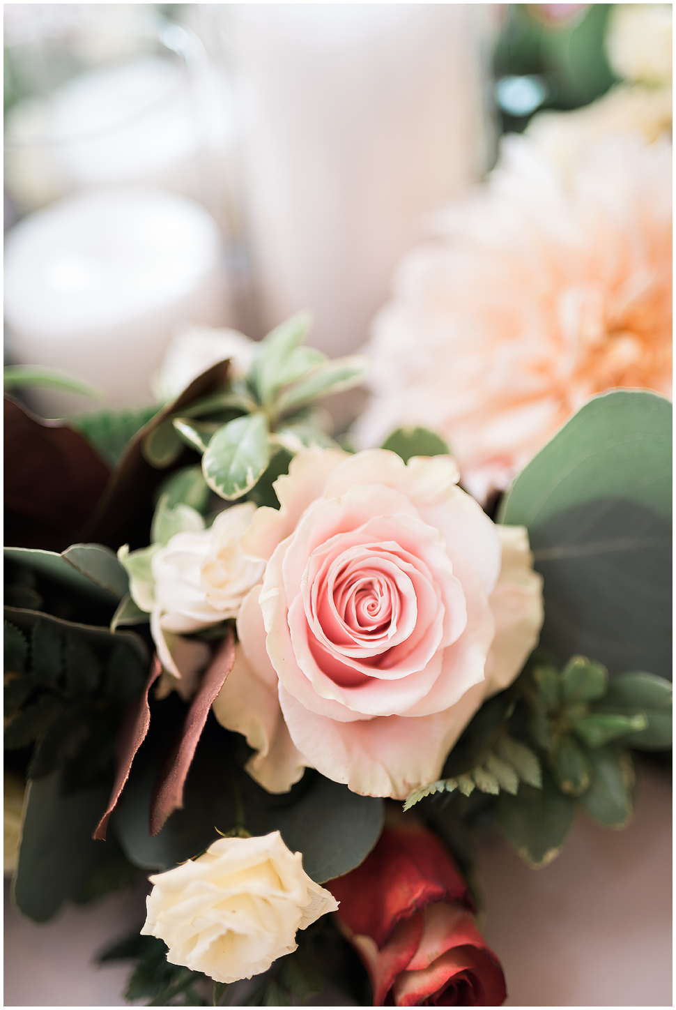 Close up of bridal bouquet showing light pink rose. 