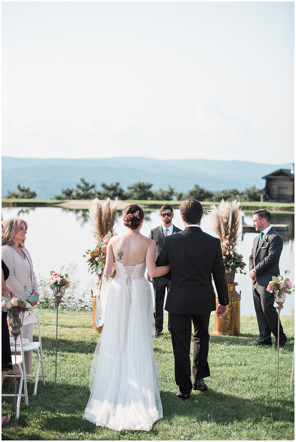 Shot from behind- Dad walks bride down the aisle at Alyson's Orchard Summer Wedding. 