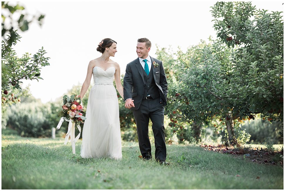 Candid and unposed portrait of a bride and groom walking at Alyson's Orchard. 