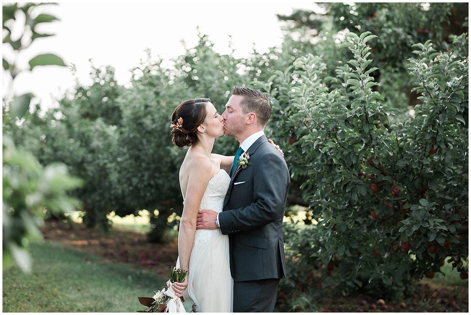 Natural and Candid photo of a bride and groom kissing in an orchard. 