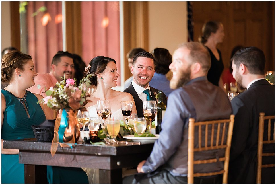Candid photo of bride and groom at head table during their reception. 