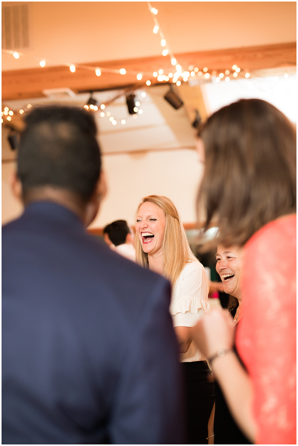 guests laughing at wedding reception. 