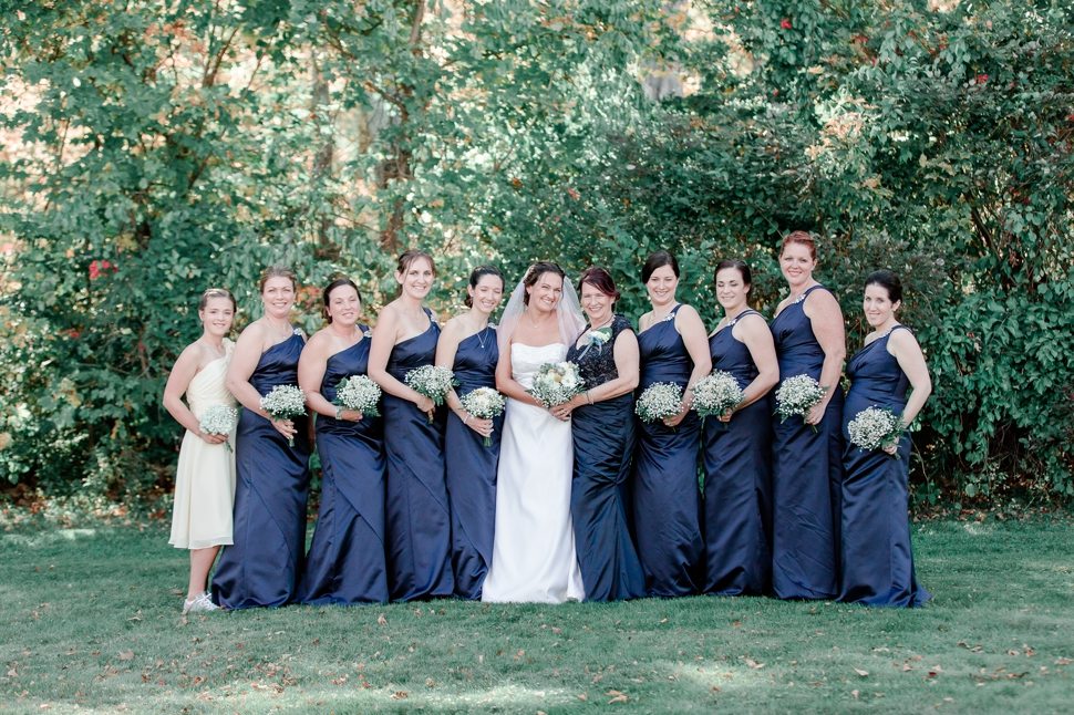 bride poses with bridesmaids in blue dresses with ivory bouquets for a group photo before the wedding ceremony
