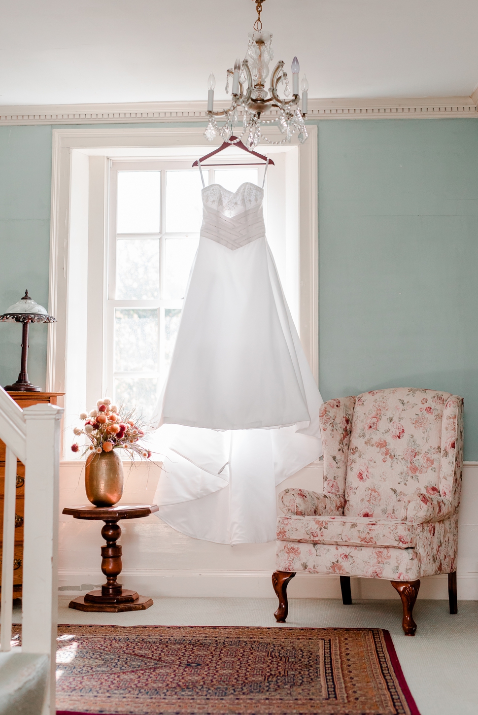 wedding dress hanging up in bridal suite next to vintage chair at the Grand View Inn Resort, Jaffrey NH