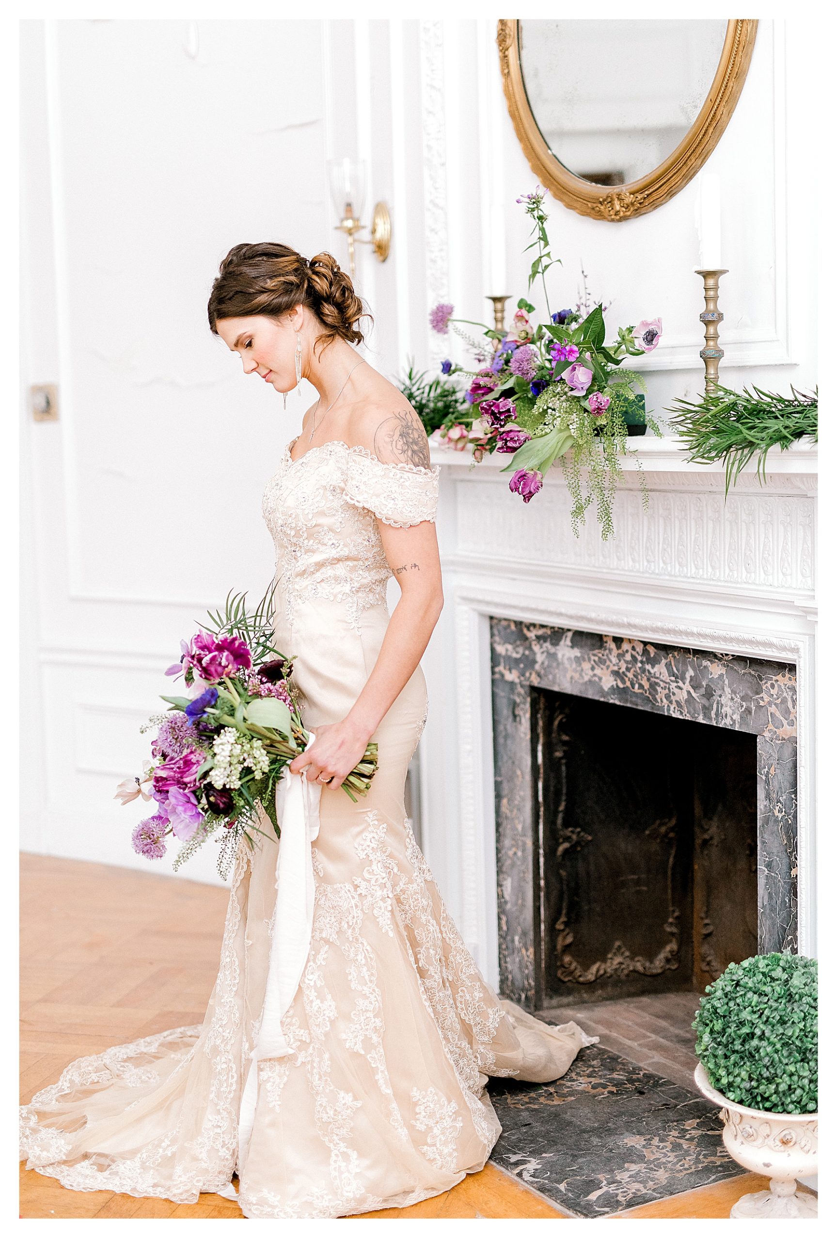 Winter Wedding at Aldworth Manor in Harrisville NH- showing a bride wearing a champagne colored dress standing in front of a fireplace. 