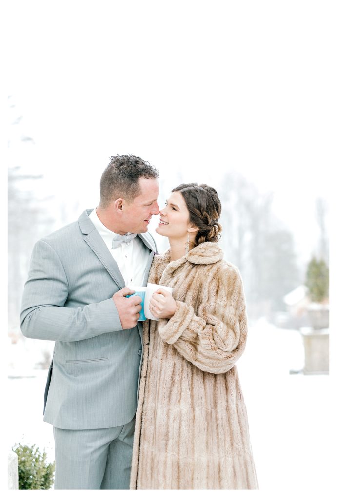 Bride and Groom drink hot cocoa outside on a snowy day during their winter wedding at Aldworth Manor