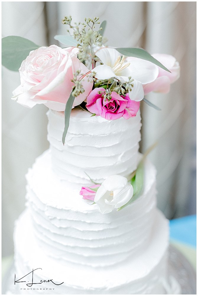 Custom designed white wedding cake with pink and white flowers on top. 