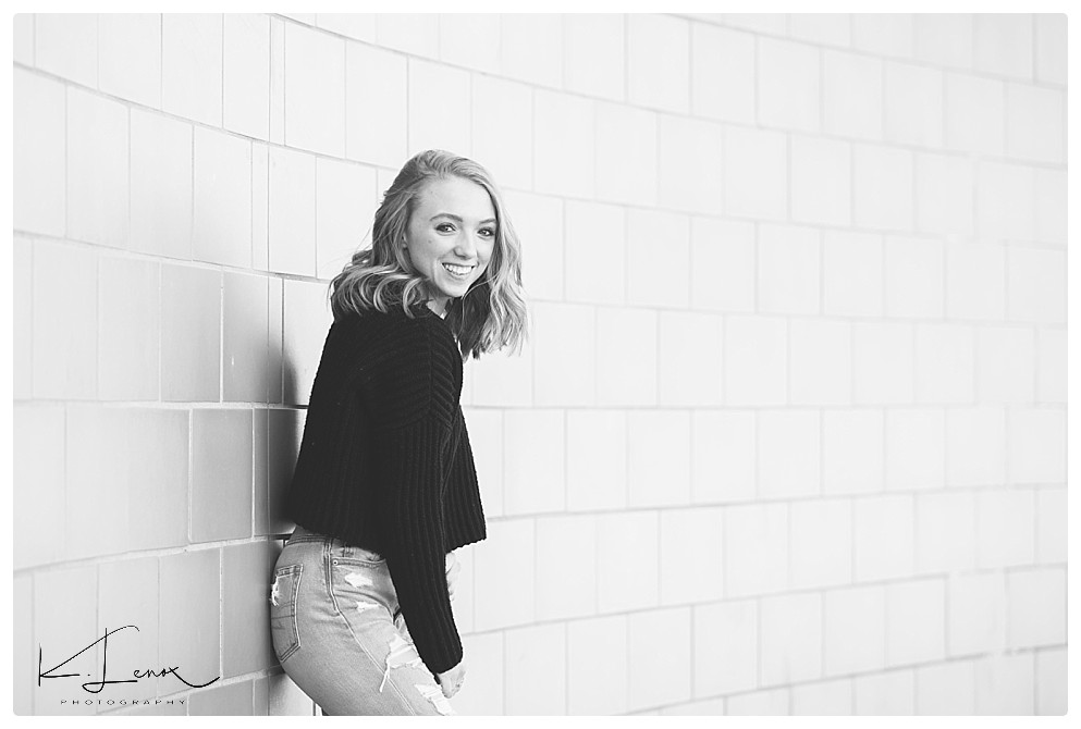 Keene Photographers- K. Lenox Photography captured a black and white photo of a senior girl against a wall. 