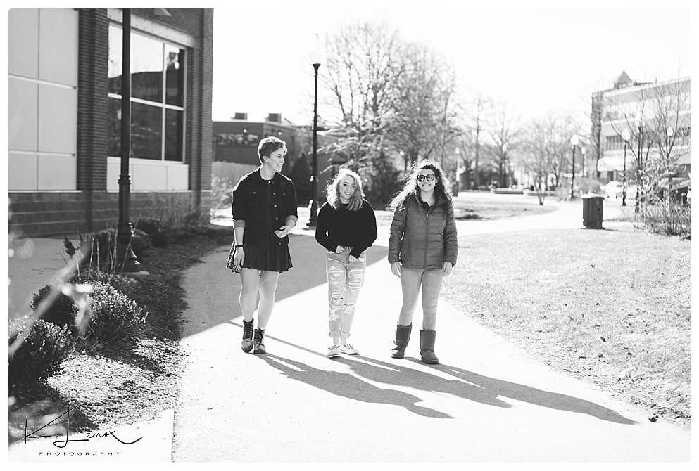 Keene Photographers take a black and white photo of three senior girls walking and laughing in downtown Keene NH. 