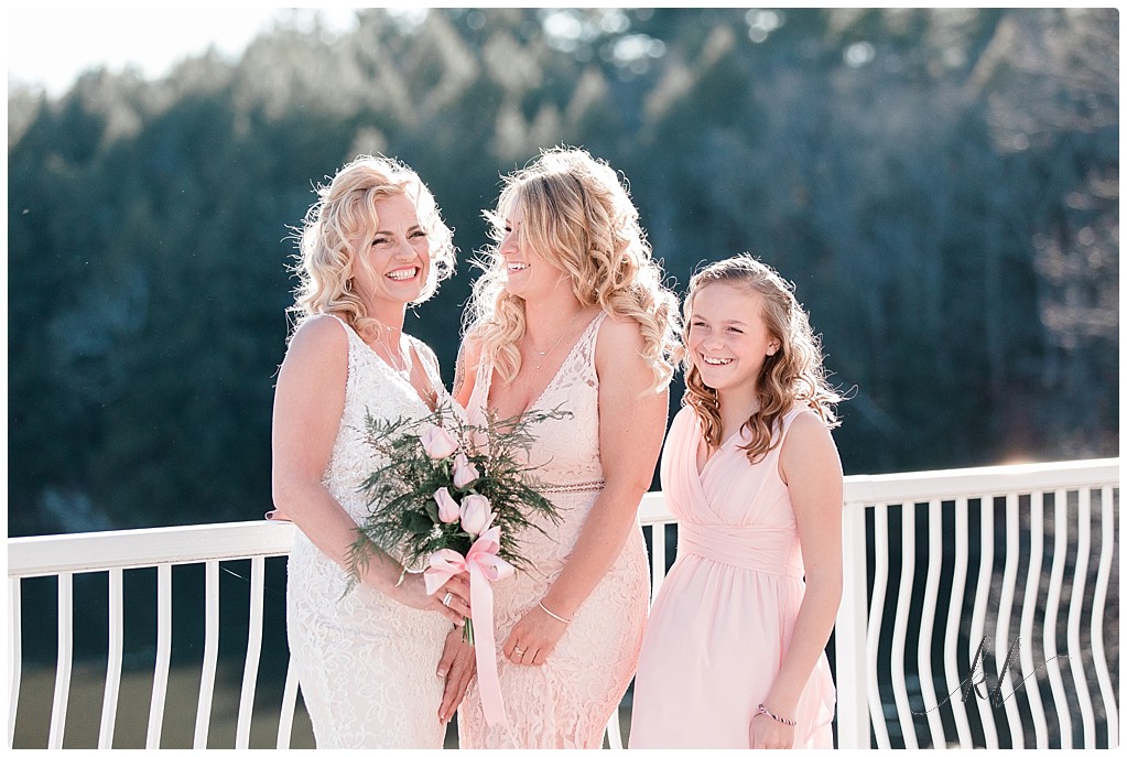 Photo of Bride holding her pink Rose bouquet and her two daughters wearing light pink bridesmaids dresses. 