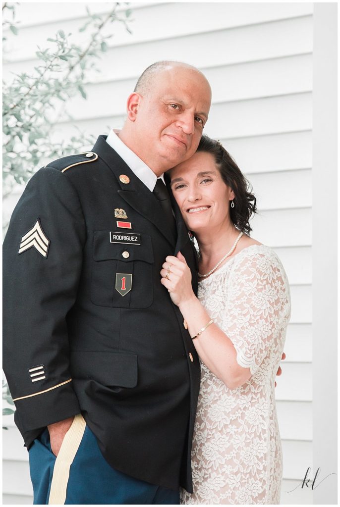 Portrait of husband in dress blues and his wife in a simple white lace dress on their 10 year vow renewal celebration day. 