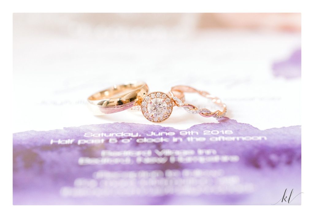 detail photo of Yellow Gold wedding rings and diamond engagement ring on a purple invitation.  Light and Airy photos by K. Lenox Photo. 