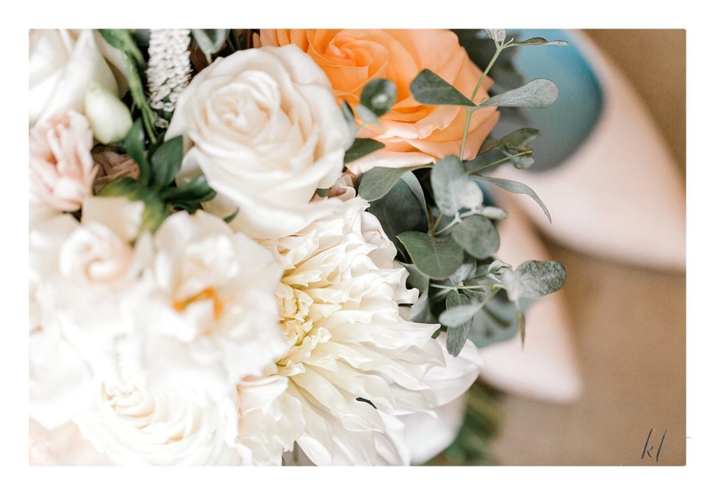 Close of of wedding bouquet showing white flowers and a peach rose.  Light and Airy photo.  