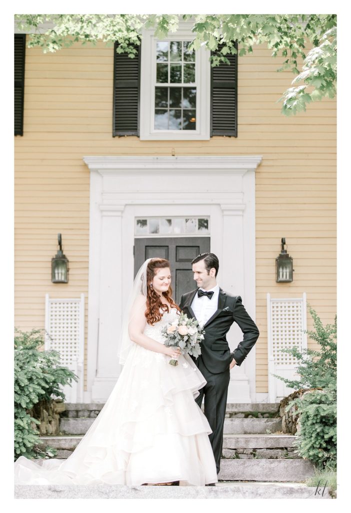 Bride and groom stand for a portrait in front of the Bedford Village inn for their summer wedding. 