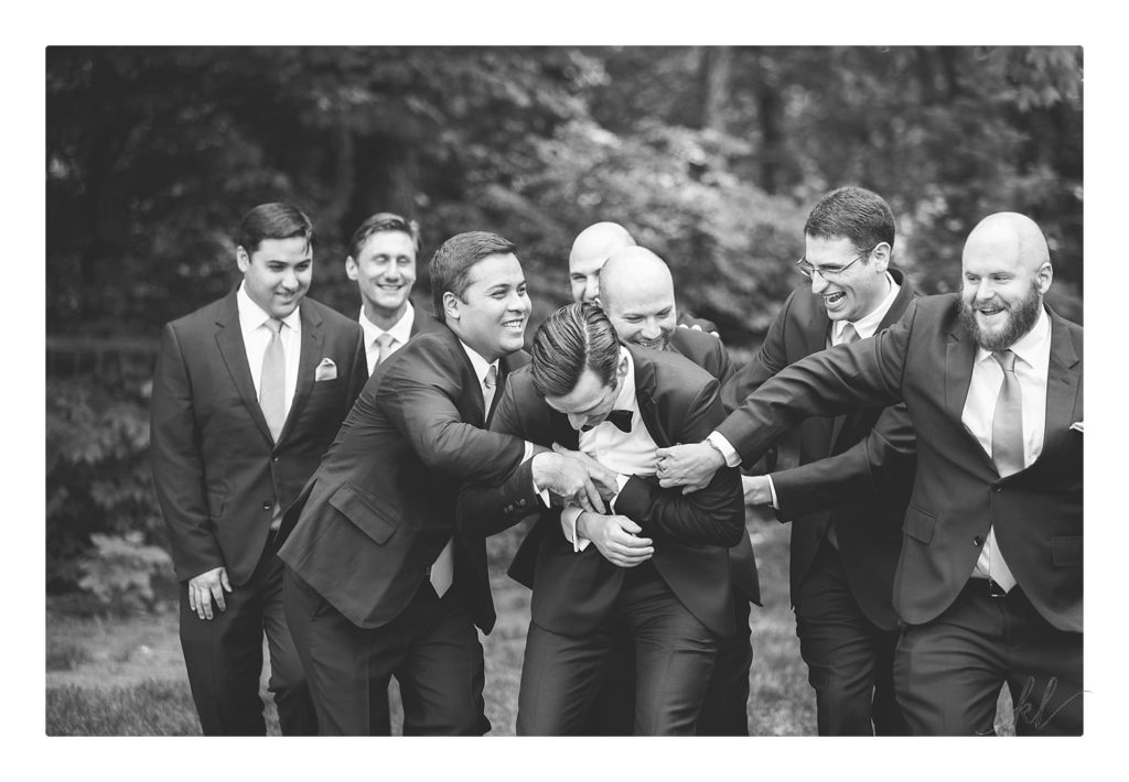 Black and White photo of a groom and groomsmen fooling around at the Bedford Village inn summer wedding. 