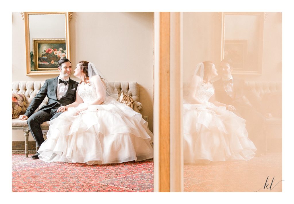 Creative portrait of a bride and groom sitting on a fancy couch at the Bedford Village Inn summer wedding. 