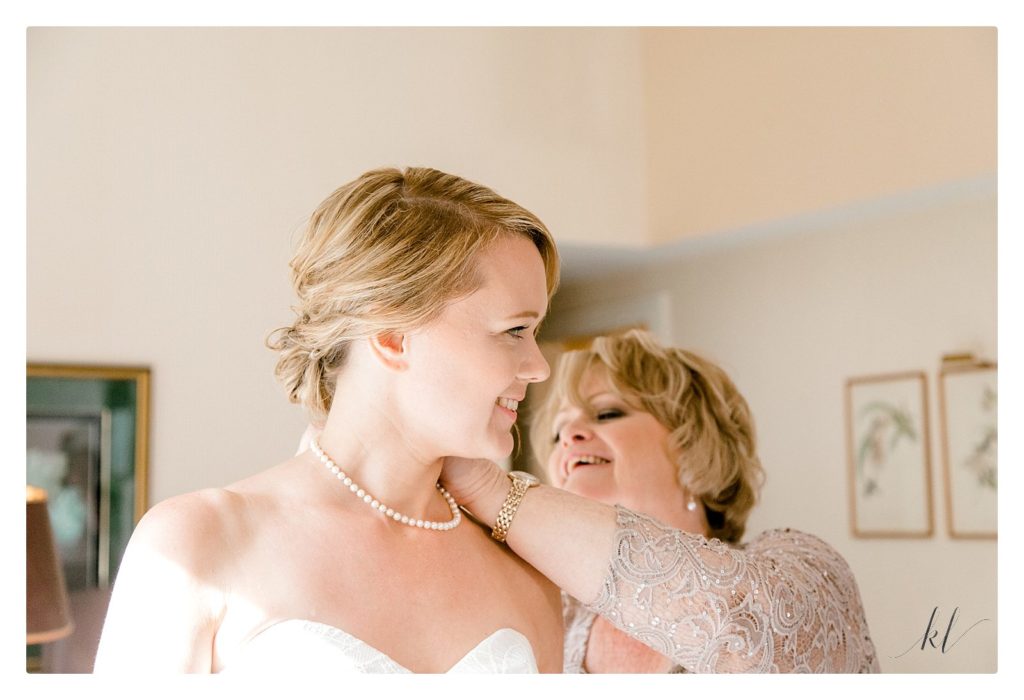 Image of mom helping bride put on her pearl necklace for her Whimsical summer wedding at the BVI. 