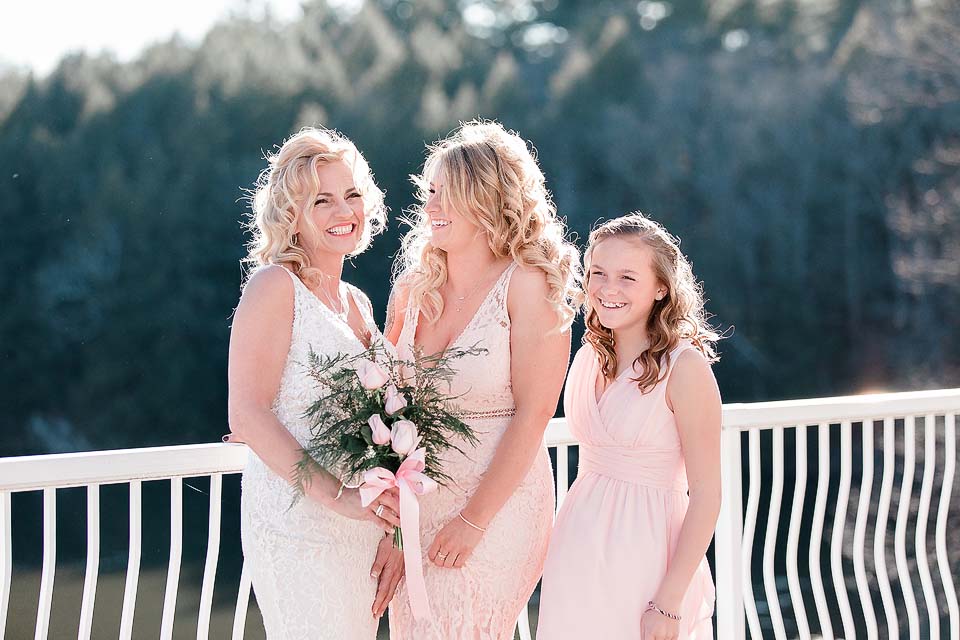 Bride and two bridesmaids wearing pink dresses stand for a photo.