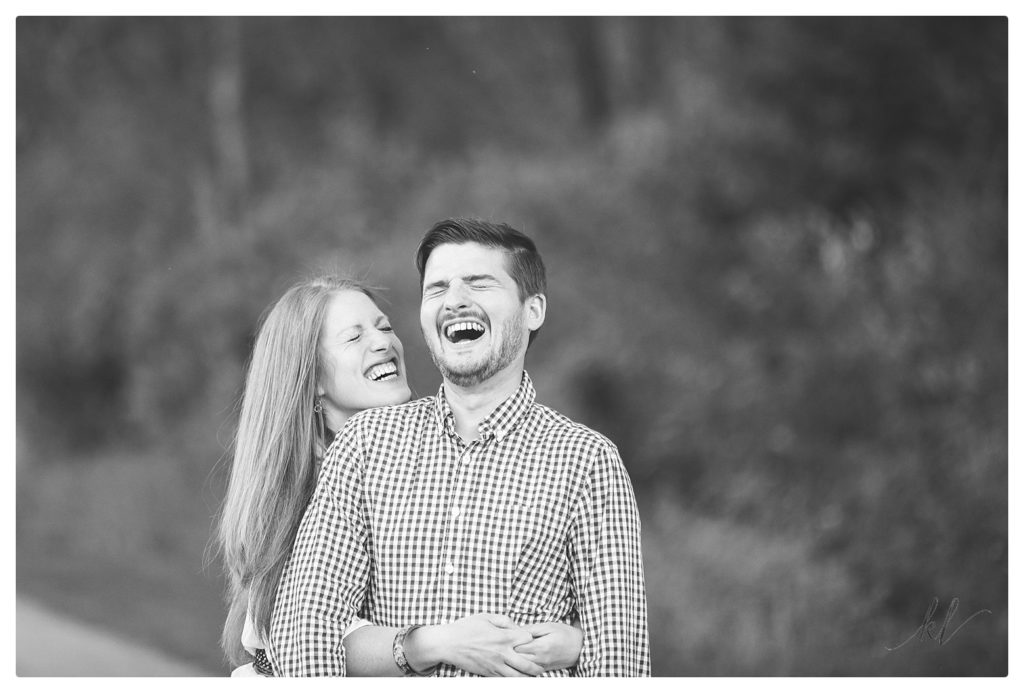 Black and White photo taken of a man and woman laughing during their engagement session. 