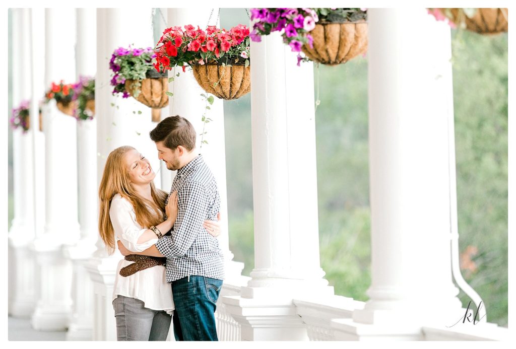 Candid and playful moment of a man and woman on the porch of the Omni Mount Washington Resort during their engagement session. 
