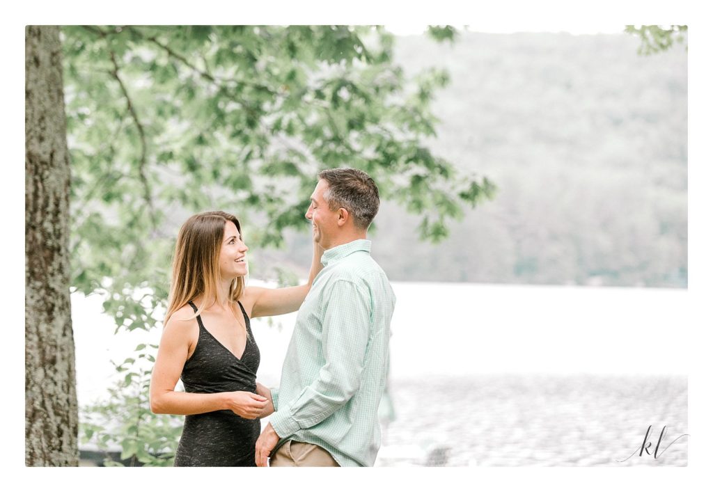 Woman wipes tear away from her fiance during their rustic engagement photos session in NH.