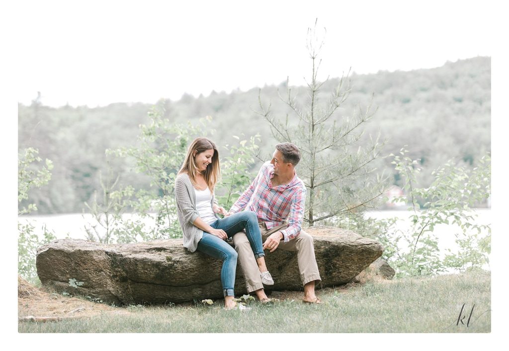 Man and Woman sitting on a Rock and laughing during their Rustic Engagement Photos Session. 