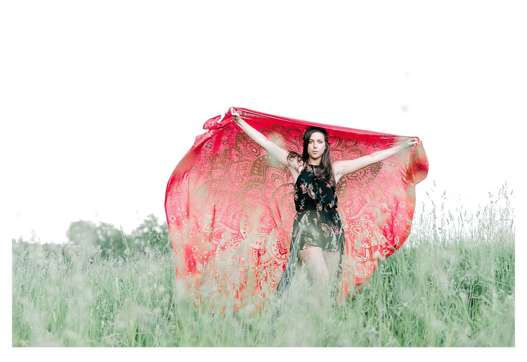 Bohemian Inspired Photoshoot- showing a girl holding a red decorative wrap as it flows in the wind. 