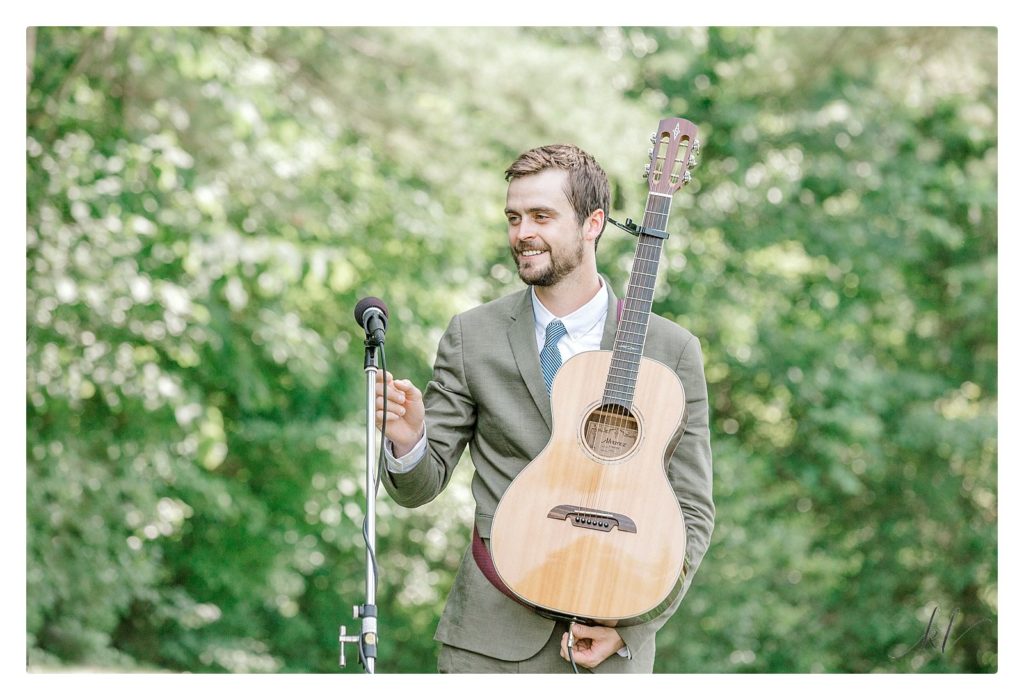 Man holds guitar during a Casually elegant backyard wedding. 
