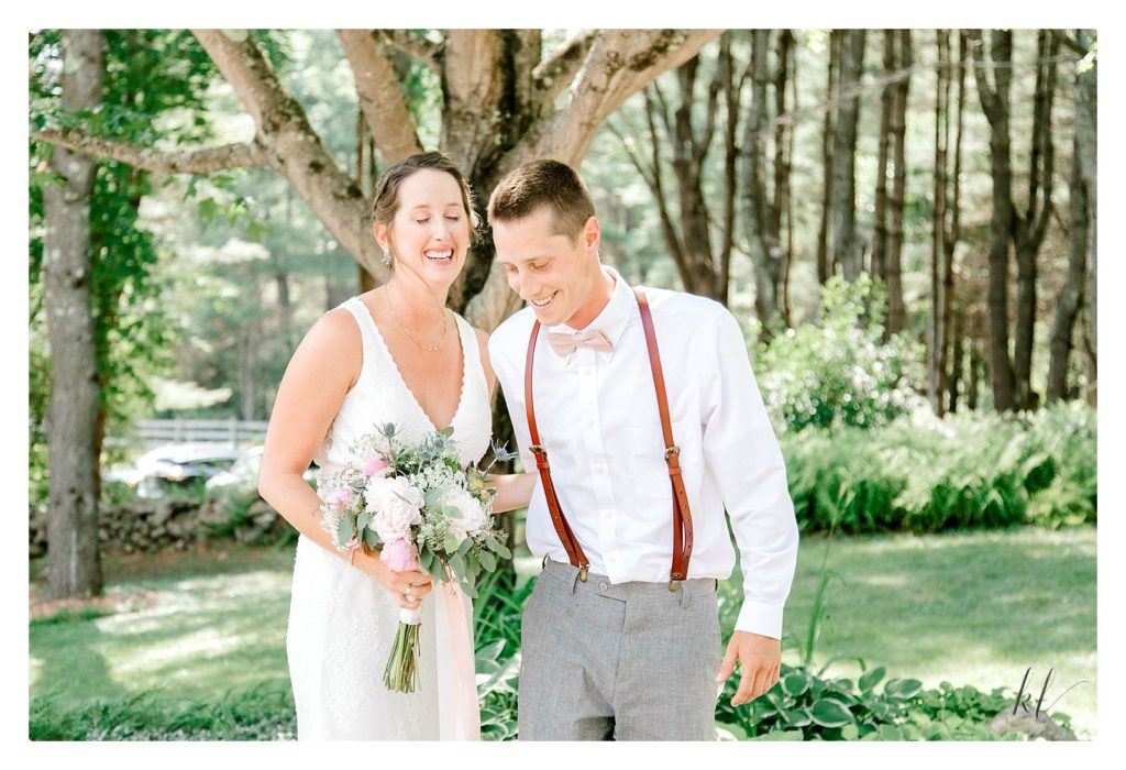 A candid photo of A bride holding a floral bouquet laughs with her brother wearing leather suspenders. 