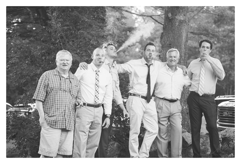 Black and White photo of wedding guests (men) smoking cigars. 