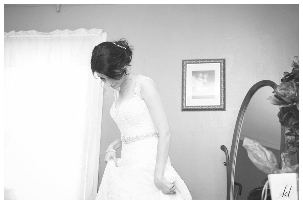 Black and White photo of a bride getting into her wedding gown designed by David Tutera. 