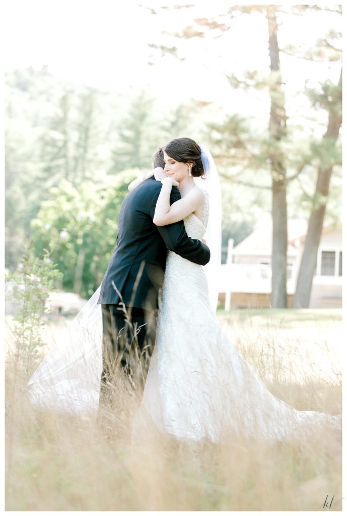 Light and Airy photo of a bride hugging her groom at the Keene Country Club Summer Wedding. 