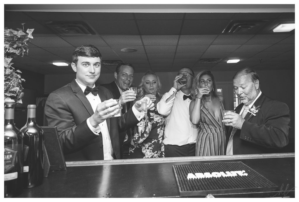 Groom and his family take a shot of whiskey at the bar during his Keene Country Club wedding reception. 