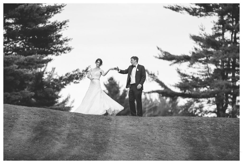 Black and white candid image of a bride and groom dancing on a hill at the Keene Country Club during their summer wedding. 