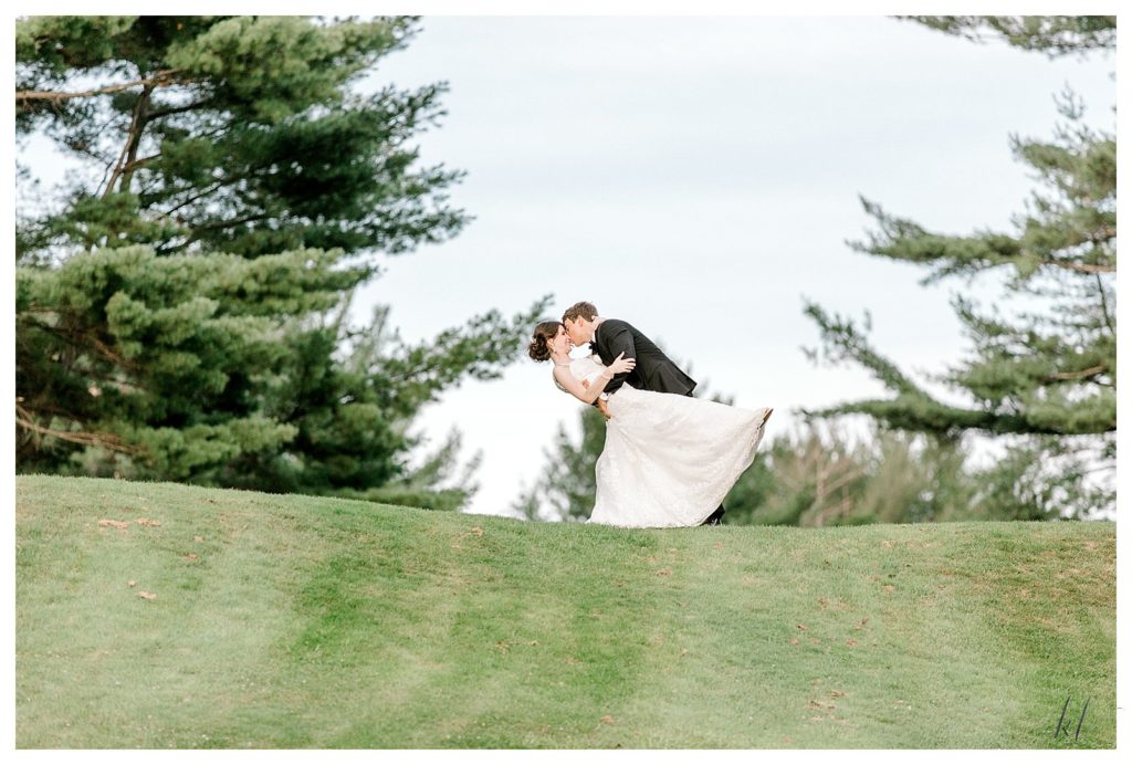 Groom dips his bride for a portrait at the Keene Country Club. 