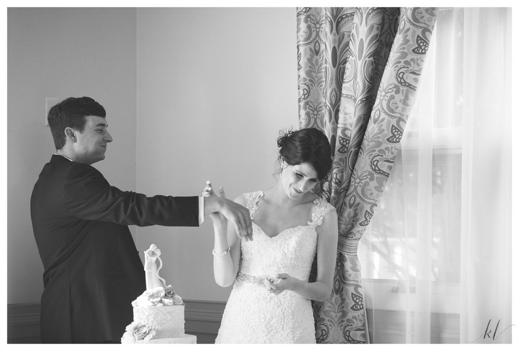 Black and white photo of a bride and groom flirting a little bit during the cake cutting ceremony at the Keene Country Club. 