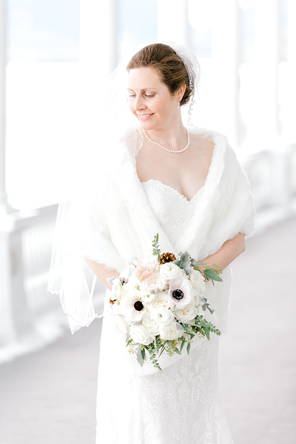 Bridal Makeup for a Winter Wedding- Bride with white shawl stands on the porch of the Omni Mount Washington Resort.